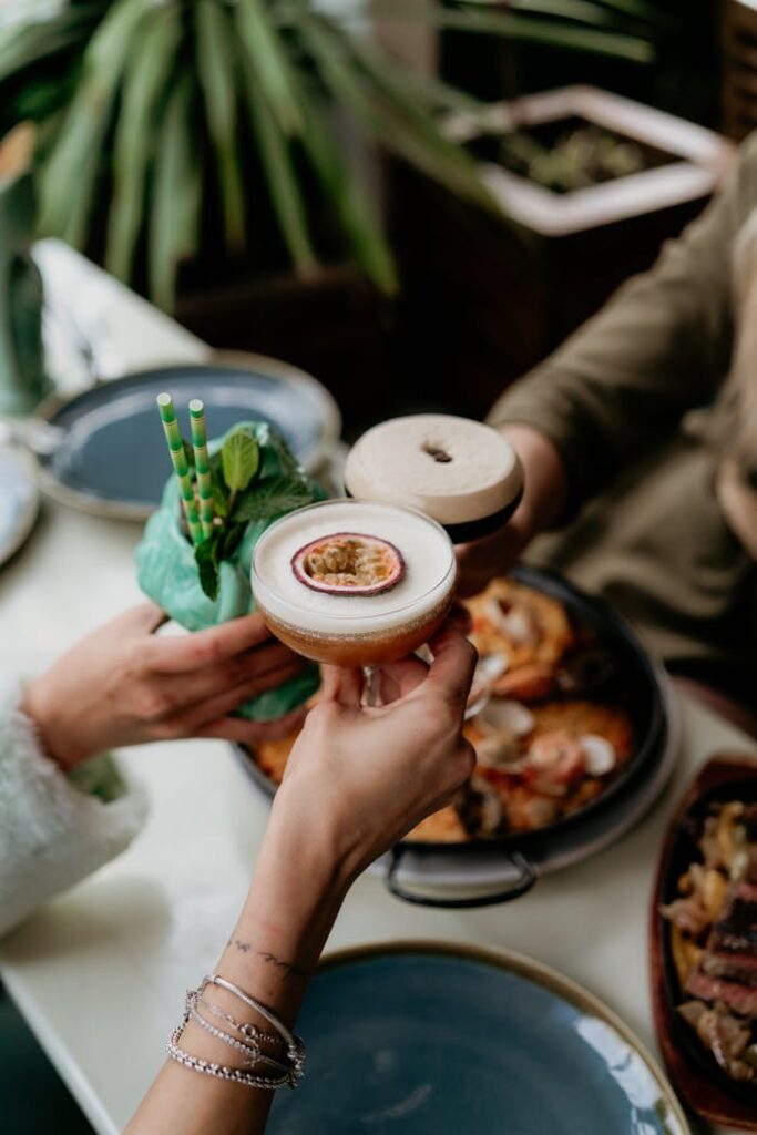 People Clinking Glasses over the Table with Food